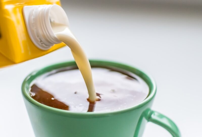 Pouring plant-based milk to a cup of coffee
