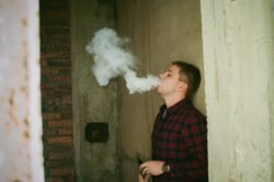 Boy vaping in alley regarding whether JUUL pods are bad for you