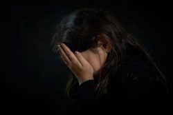 Girl with hands over her face regarding the First Nations Children class action lawsuits moving forward 