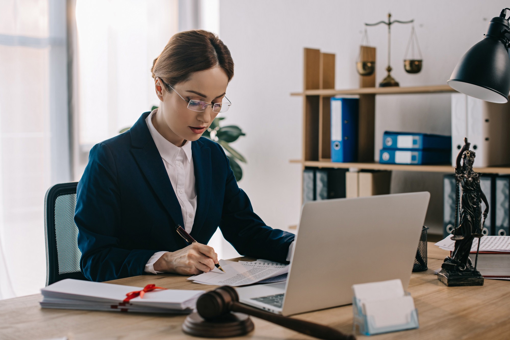lawyer working at her desk regarding information on who covers the cost of a class action lawyer