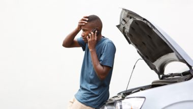 Man standing next to a stalled car regarding the Denso fuel pump defect