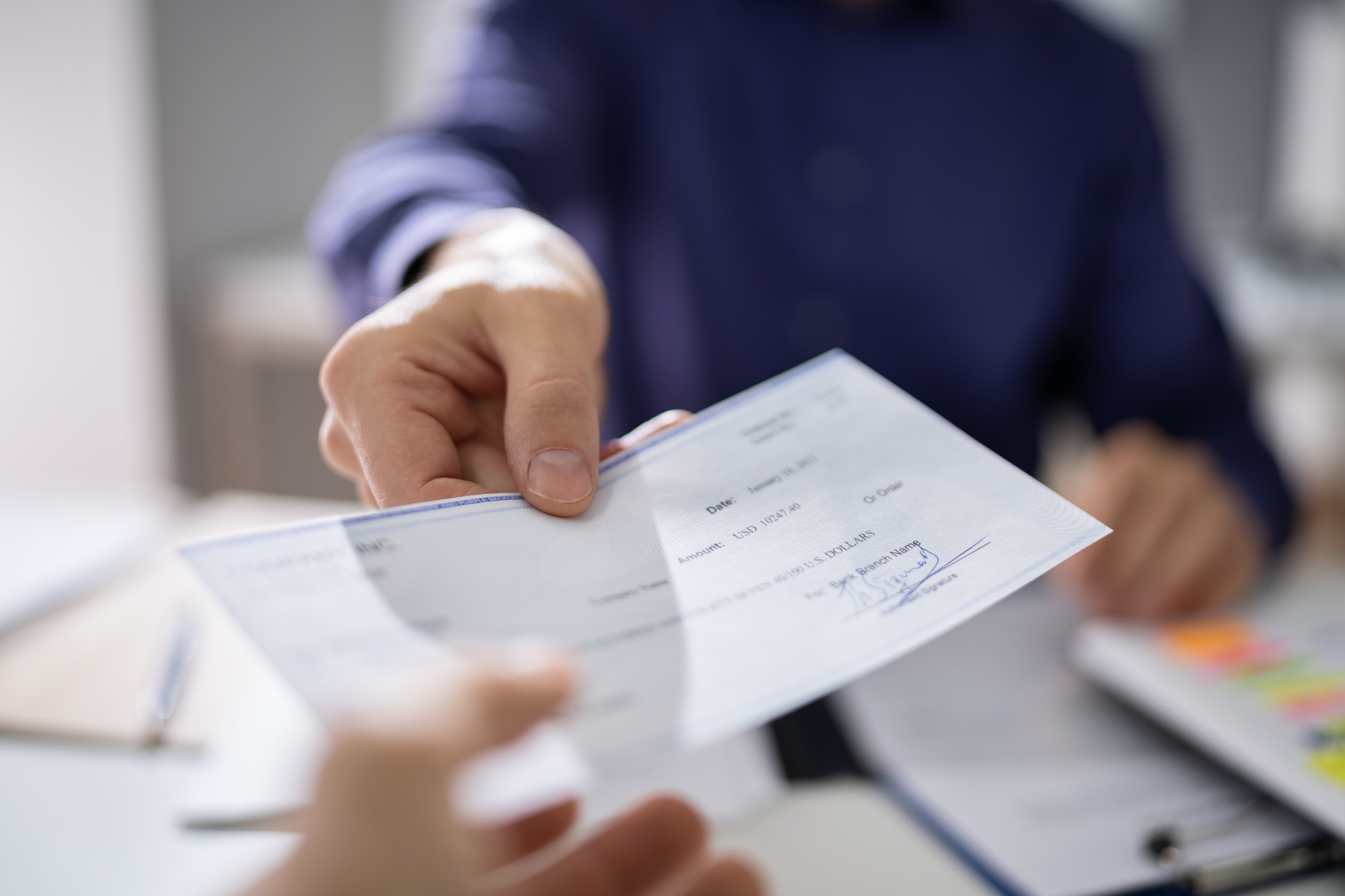 Person handing over cheque regarding the NSF fee class action lawsuit