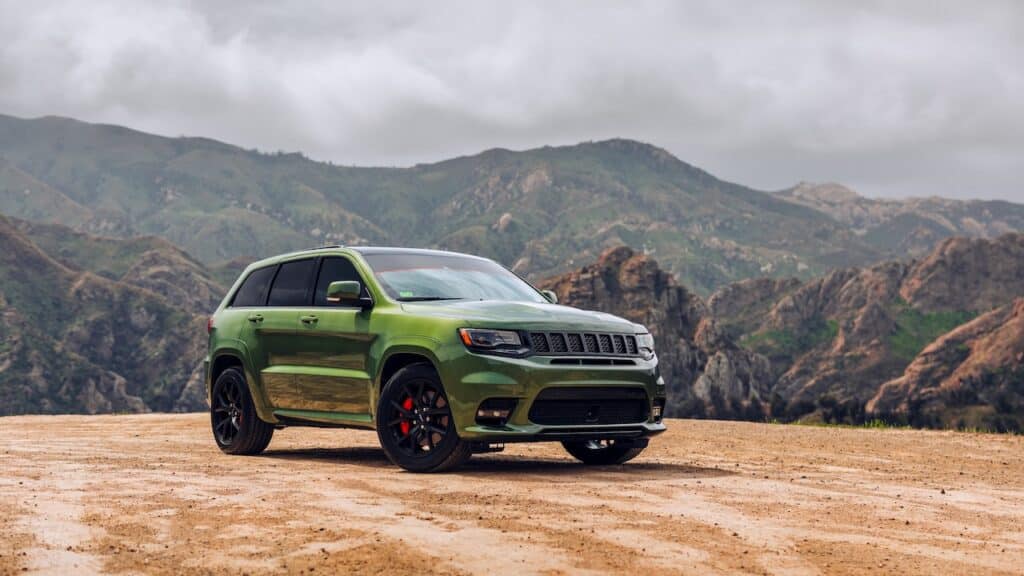Green Jeep Grand Cherokee SRT showing the passenger side of the car with mountains in the background