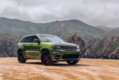 Green Jeep Grand Cherokee SRT showing the passenger side of the car with mountains in the background