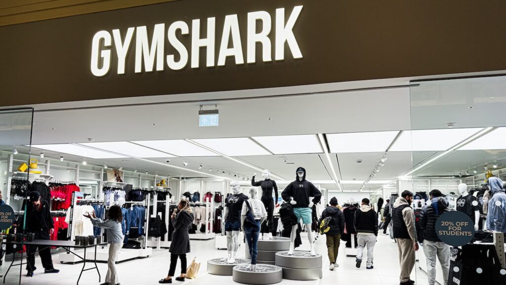 Inside the Gymshark shop, shoppers browse athleticwear around mannequins and bright lighting.