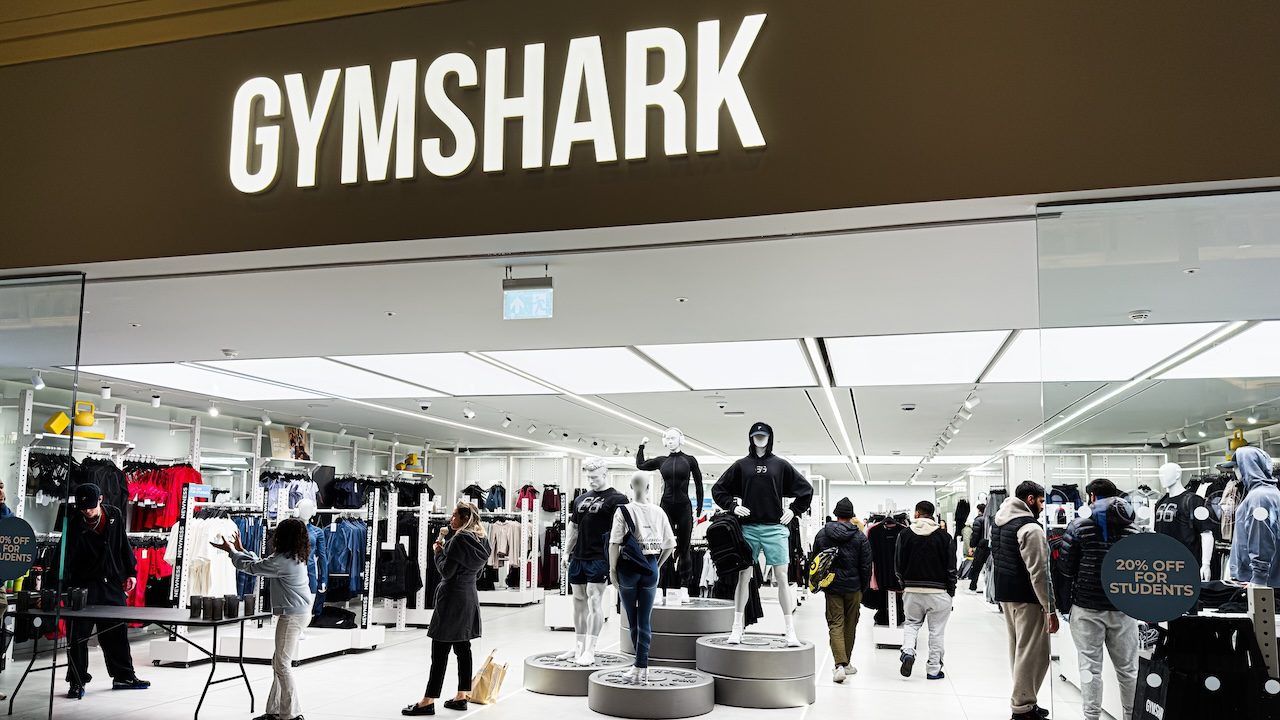 Inside the Gymshark shop, shoppers browse athleticwear around mannequins and bright lighting.