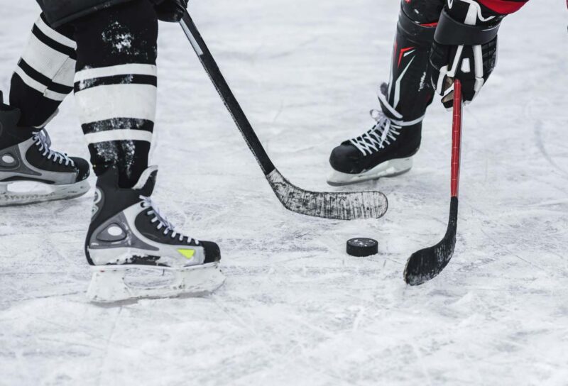 Close up of hockey players with a hockey puck, representing the NHL class action lawsuit.