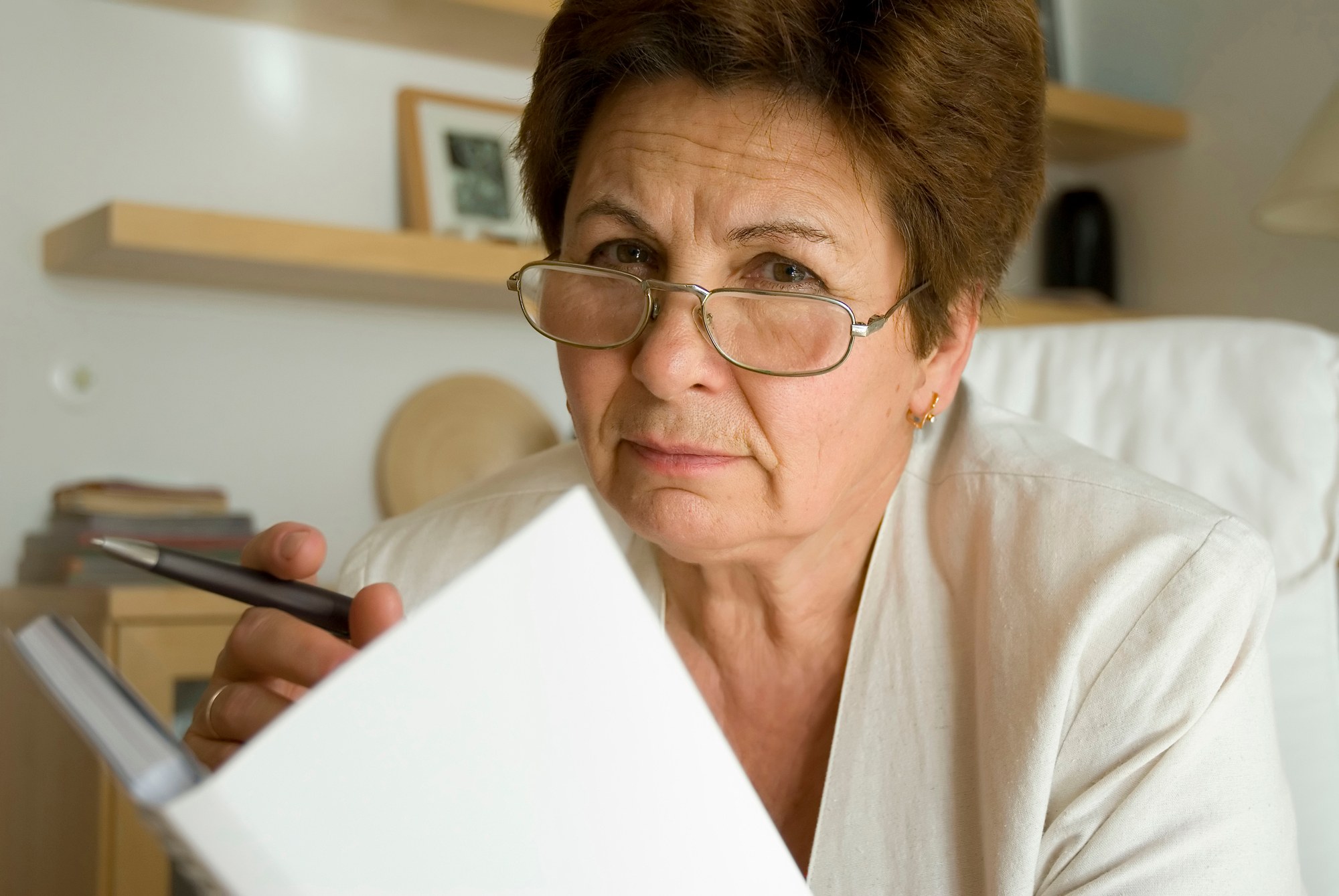 Woman looking concerned holding a pen regarding the allegedly problematic Indian day school claim form 